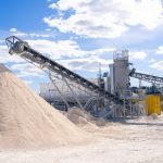 Planta industrial de processamento mineral com esteiras transportadoras ao ar livre.