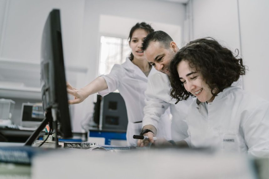 Grupo de pesquisadores trabalha em conjunto diante de um computador em um laboratório moderno.
