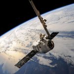 Satélite em órbita sobre a Terra, com nuvens e o espaço ao fundo.