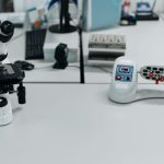 Microscópio e frascos dispostos em um laboratório de pesquisa científica.