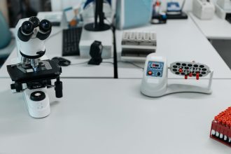Microscópio e frascos dispostos em um laboratório de pesquisa científica.