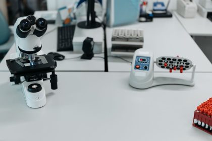 Microscópio e frascos dispostos em um laboratório de pesquisa científica.