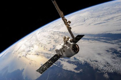 Satélite em órbita sobre a Terra, com nuvens e o espaço ao fundo.