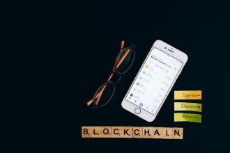 Smartphone exibe informações do mercado de criptomoedas sobre fundo escuro com elementos visuais associados à tecnologia blockchain.