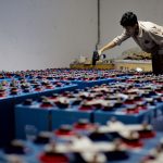 Trabalhador inspeciona fileiras de baterias industriais dentro de uma instalação fabril