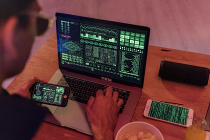 Pessoa trabalhando com software de cibersegurança em um laptop e um smartphone.